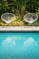 Une paire de chaises de jardin vintage Acapulco au bord de la piscine dans le jardin californien. Conçu par Falling Waters Landscape, inc Ryan Prange, New Port Beach, Californie, États-Unis.