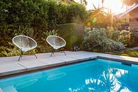 Une paire de chaises de jardin vintage Acapulco au bord de la piscine dans le jardin californien. Conçu par Falling Waters Landscape, inc Ryan Prange, New Port Beach, Californie, États-Unis.
