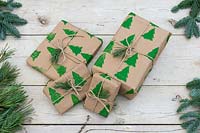 Pile de cadeaux de Noël enveloppés de papier d'emballage imprimé à la main et attachés avec de la ficelle