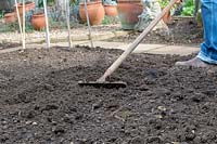 Jardinier ratisser le sol dans un potager.