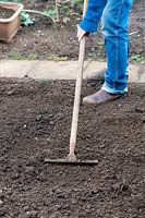 Jardinier ratisser le sol dans un potager.
