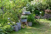 Décoration de jardin vintage avec pots en étain, chaises anciennes et vieux arrosoirs