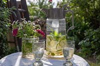 Deux verres d'eau citronnée avec bouquet de fleurs, mis sur table dans un jardin
