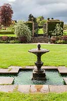 Fontaine et piscine à côté de la maison. Jardin Miserden, près de Stroud, Gloucestershire, Royaume-Uni.
