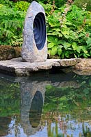 Vue de la sculpture en pierre focale sur les rochers reflétée dans une piscine. 'At One With ... A Meditation Garden', conçu par Peter Dowle, RHS Malvern Spring Festival, 2017.