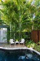 Ensemble de chaises de jardin et table sur terrasse en bois en bois au bord de la piscine, entourée de palmiers tropicaux. Résidence Von Phister, Key West, Floride, USA. Conception de jardin par Craig Reynolds.