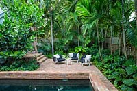 Mobilier de jardin blanc dans un jardin tropical pavé. Jardin classique de Key West, conçu par Craig Reynolds. Key West, Floride, États-Unis.