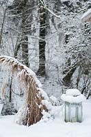 Une lanterne enneigée et un Miscanthus au milieu de la neige.