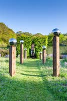 Voir le long du chemin d'herbe avec une avenue de globes de miroir en acier inoxydable montés sur des poteaux en bois