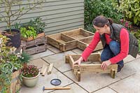 Femme assemblant les coins de la jardinière surélevée, assemblant les morceaux de chaque joint à demi-tour