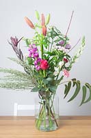 Bouquet de différents types de fleurs dans un vase en verre.