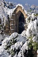 Porte en pierre dans la neige à Burrow Farm Garden, Dalwood, Devon, UK.