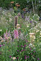 Poteaux de clôture avec des hôtels d'insectes le long du parterre de fleurs vivaces. RHS Hampton Court Festival 2019.