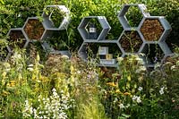 Un jardin planté pour attirer la faune. Les formes contemporaines en nid d'abeille sont présentes dans un mur conçu pour être un habitat pour les insectes, en particulier les abeilles. RHS Hampton Court Palace Garden Festival 2019. Commanditaire: Warner's Distillery.