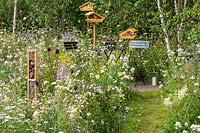 Un coin salon dans un jardin naturaliste respectueux de la faune avec des fleurs sauvages et des jardins de chalets, offrant un habitat pour la faune, les oiseaux, les insectes et les abeilles. RHS Hampton Court Palace Garden Festival 2019.