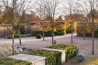 Jardin clos conçu par Brita von Schoenaich mettant en vedette Amelanchier x grandiflora 'Robin Hill', des blocs de boîte taillés, des sphères en pierre et des plantes vivaces et des herbes herbacées au Marks Hall Gardens en automne.