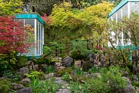 Jardin relaxant avec plan d'eau entouré d'Acer palmatum, de boules de mousse, d'Iris 'Shirley Pope', de Pieris japonica 'Little Heath' et d'un bâtiment au toit vert - Switch, RHS Chelsea Flower Show 2019