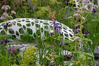 Iris sibirica 'Persimmon' avec Euphorbia et sculpture de Liam Hopkins en arrière-plan - The Manchester Garden, RHS Chelsea Flower Show 2019