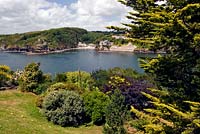 Vue sur jardin avec parterre de fleurs à la mer et la rive de l'autre côté avec une crique