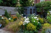 Petit jardin avec moustiquaire à partir de clôtures horizontales à lattes, pavillon d'été, arbre en grand pot. La plantation en plates-bandes comprend: Phlox 'David', Achillea 'Moonshine', Stipa arundinacea, Helenium 'Moerheim Beauty ' et Alchemilla mollis