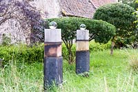 Colonnes de bois surmontées de sphères de verre dans les hautes herbes à Broadwoodside, Gifford, East Lothian en Ecosse.