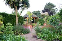 Le jardin exotique à Abbeywood Gardens. Les plates-bandes contiennent des plantes dont Salvia coccinea 'Lady in Red' Bergenia Hemerocallis Cordyline australis et Phormium