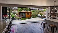 Une vue sur un jardin contemporain, avec salon de jardin, depuis la cuisine