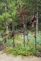 Fleurs artisanales en métal sous Pinus nigra - Pin d'Autriche - avec couvre-sol