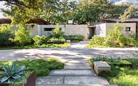Jardin avant d'une maison contemporaine avec chemin de calcaire et plantation architecturale dont Agave en parterres de fleurs en acier