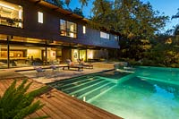 Vue sur terrasse en bois et piscine vers terrasse et maison contemporaine