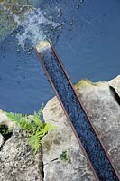 Un ruisseau surélevé sur un rocher, déversant de l'eau dans un étang