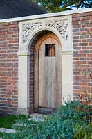 Détail de la porte avec un design botanique décoratif en relief en plâtre sur l'arc.