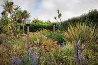 Le jardin Beth Chatto avec table d'oiseaux en dôme de verre, herbes, échinacée, Rudbeckia, Perovskia, Phormium, Cordyline et Crocosmia