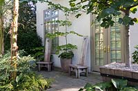 Petite entrée formelle avec des chaises en bois et des jardins en pot à l'extérieur de la maison Chanticleer