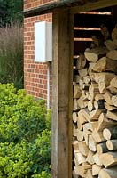 Magasin de bois de chauffage à côté du parterre d'Alchemilla mollis avec boîte étanche pour l'électricité du jardin sur le mur - Open Gardens Day 2013, Middleton, Suffolk