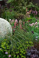 Plantation d'herbacées entourant une caractéristique sphérique faite de galets dans un parterre de jardin - RHS Malvern Spring Festival 2014
