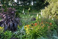 Le jardin en noir et blanc avec une touche de Hemerocallis orange - lis du jour. Y compris les phormiums, un sureau à feuilles foncées - Sambucus racemosa cv., Digitales blanches - Digitalis purpurea f. albiflora et poire pleureuse Pyrus salicifolia 'Pendula'