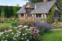 La roseraie arbustive. Parterres de roses se mêlant à des plantes vivaces herbacées telles que la menthe des chats et des géraniums rustiques, conduisant à la Maison du Thé, une folie du C19. Arley Hall, Cheshire, Royaume-Uni.
