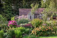 Roseraie romantique et maison en pierre. Parterre de fleurs mélangé avec diverses roses standard dans le jardin privé de David Austin Jnr. juin
