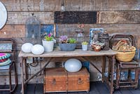 Une table dans la salle à manger couverte décorée de pots de plantes succulentes et de divers objets récupérés.