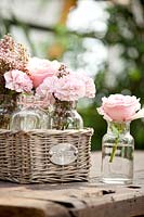 Rose 'Rosita', Dianthus 'Kristine' et Erica glacialis dans de petits vases en verre