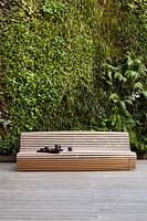 Banc en bois moderne contre mur végétal vivant dans un jardin moderne.