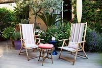 Chaises de terrasse en bois sur la terrasse avec Olea europaea derrière