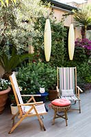 Chaises de terrasse en bois sur la terrasse avec Olea europaea derrière