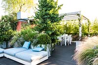 Terrasse en bois avec des plantes dans des auges qui filtrent les espaces de vie et de repas