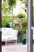 Terrasse carrelée vue de la maison, coin salon et plantes en pot