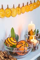 Étagère décorée d'oranges clouées de clous de girofle, de bougies et de Laurus nobilis - Baie, au-dessus de tranches d'orange chevillées en ligne