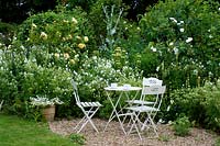 Meubles de style café blanc sur une zone de gravier dans le jardin du chalet.
