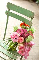 Bouquet de visnaga daucoides, renoncules, pois de senteur et roses sur une chaise en bois
