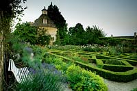 Jardin Parterre avec Buxus - Boîte - parterres bordés de fleurs, bancs avec Lavendula - Lavande et Alchemilla mollis, pigeonnier en arrière-plan